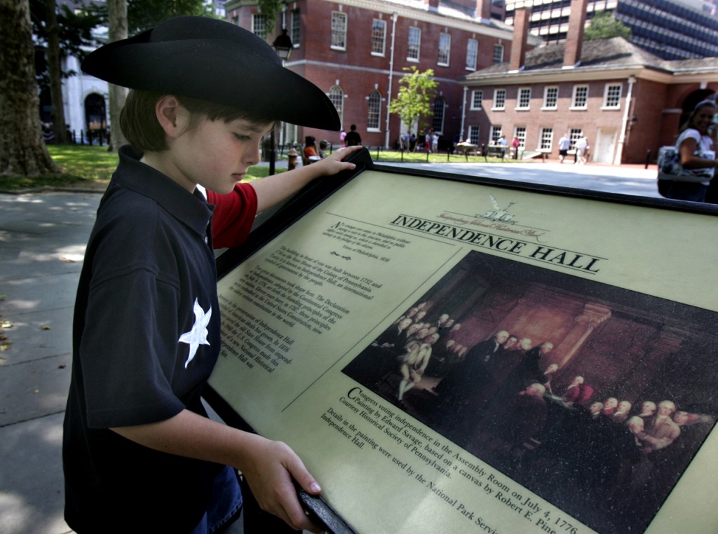 1776年に独立宣言が採択された独立記念館についての説明を読む男の子。独立記念館があるインディペンデンス国立歴史公園（ペンシルベニア州フィラデルフィア）には、毎年300万人以上の観光客が訪れる (AP Photo/Rusty Kennedy)