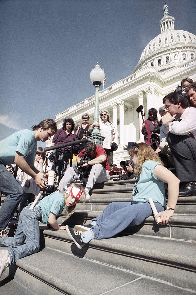 脳性まひを患った８歳の少女が、連邦議会議事堂前の階段を自力で登っている。1990年３月のデモで (AP Photo/Jeff Markowitz)