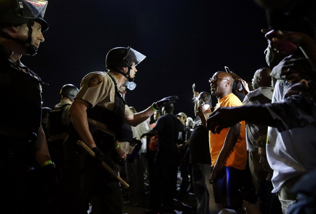 Officers and protesters face off along West Florissant Avenue, Monday, Aug. 10, 2015, in Ferguson, Mo. Ferguson was a community on edge again Monday, a day after a protest marking the anniversary of Michael Brown's death was punctuated with gunshots. (AP Photo/Jeff Roberson)