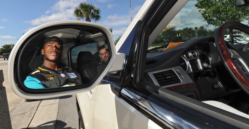 フロリダ州ジャクソンビルで配車サービス「ウーバー」を宣伝するアメリカンフットボールのスター選手アレン・ロビンソン (© AP Images)