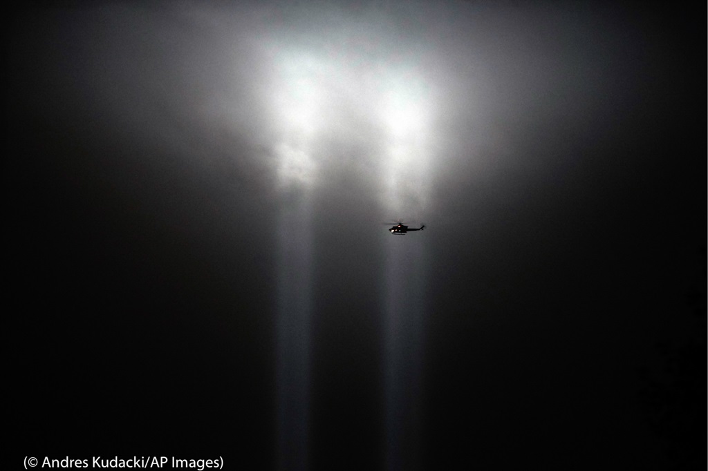 ニューヨーク市ロウアー・マンハッタンで、1機のヘリコプターが上空に伸びる「追悼の光」のそばを飛んでいる。2本の光の柱は、攻撃されたツインタワーを象徴する。