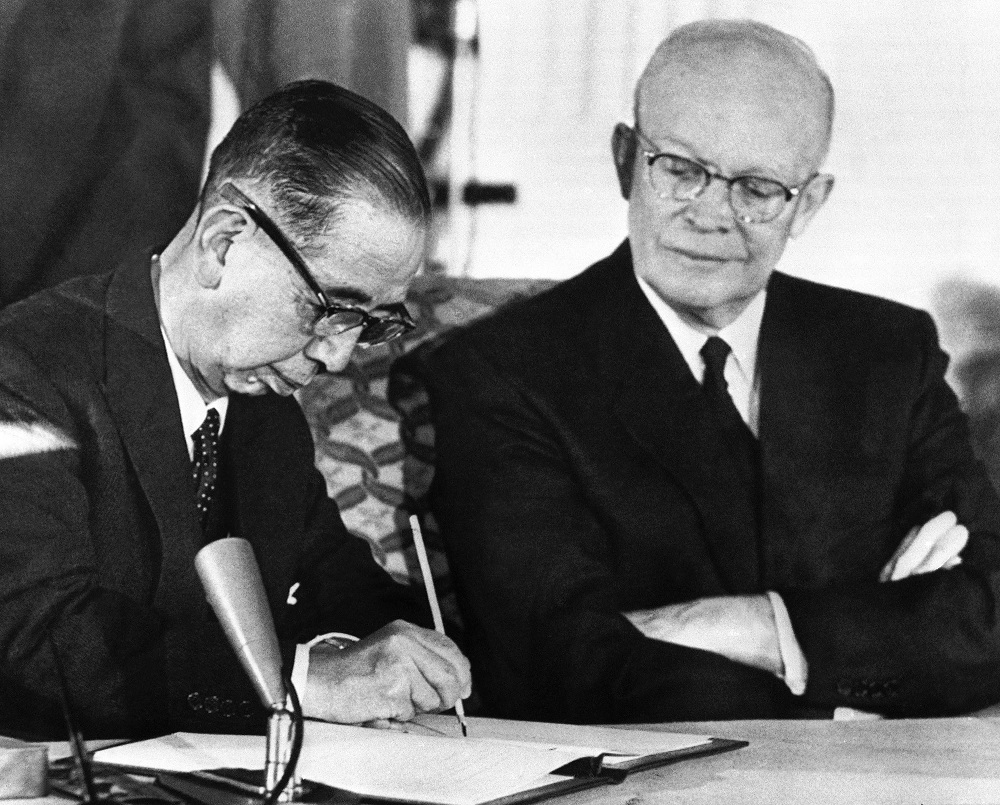アイゼンハワー大統領が見守る中、日米安全保障条約に署名する岸信介首相。1960年1月19日、ワシントンDC (AP Photo)