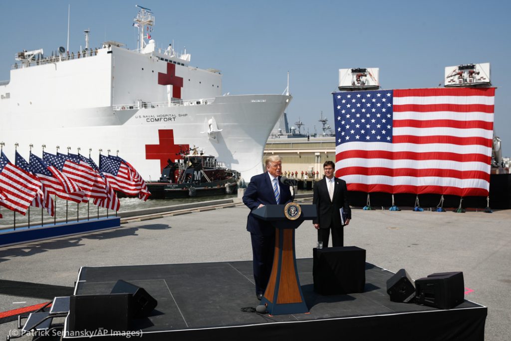 フル装備の病院船「コンフォート」をニューヨークに派遣する前、バージニア州ノーフォークで演説するトランプ大統領。右はマーク・エスパー国防長官 (© Patrick Semansky/AP Images) 