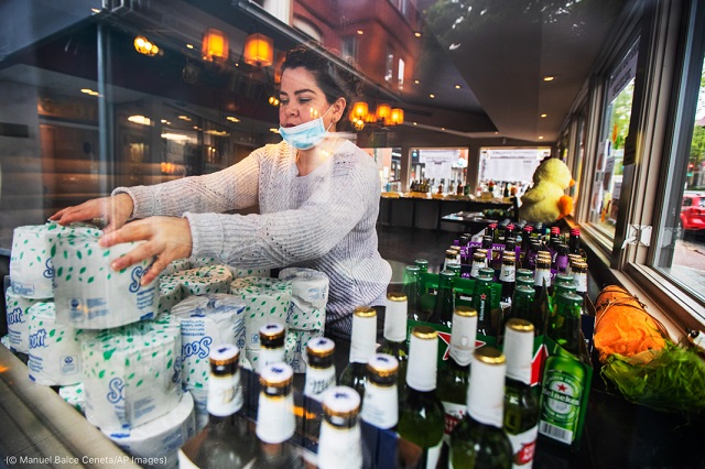 On an April day when Annie’s Paramount Steakhouse in Washington is closed, Sara Rivas works alone to arrange toilet paper for later pickup. (© Manuel Balce Ceneta/AP Images)