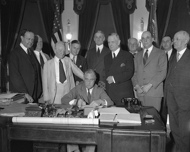 フランクリン・デラノ・ルーズベルト大統領がホワイトハウスにて法案に署名。1933年撮影 (© AP Images)