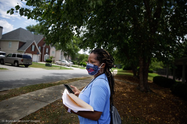 2020年7月、ジョージア州パウダースプリングスの住宅地で期日前有権者登録用紙を配布する女性 (© Brynn Anderson/AP Images)
