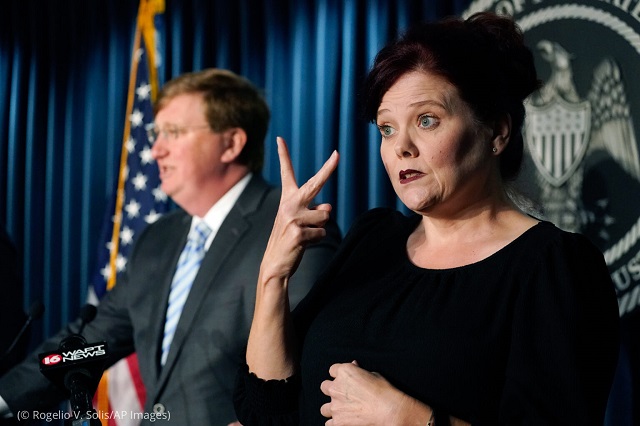 At an August press event in Jackson, Mississippi, Amy Ainsworth signs as Mississippi Governor Tate Reeves answers a reporter’s question about COVID-19. (© Rogelio V. Solis/AP Images)