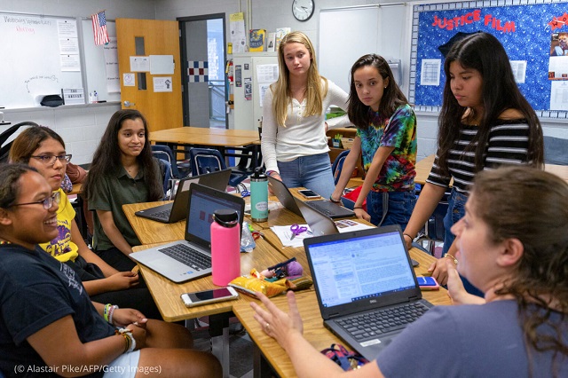 In Falls Church, Virginia, Justice High School teacher Jennifer Golobic (right) speaks in September 2019 to students with the “Girl Up” club who stock school bathrooms with free pads and tampons to push for menstrual equity. (© Alastair Pike/AFP/Getty Images)