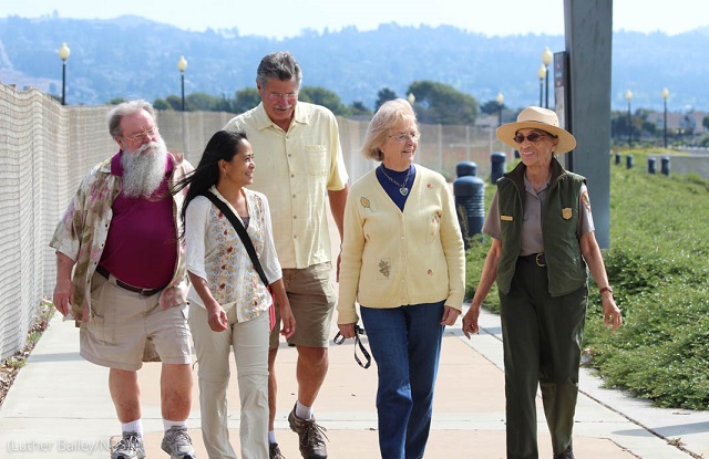 「ロージー・ザ・リベッター」教育センターの外を来場者と歩くベティ・レイド・ソスキン。カリフォルニア州リッチモンド (Luther Bailey/NPS)