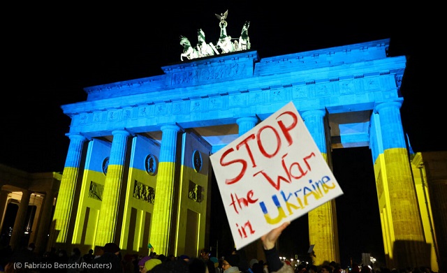 ブランデンブルク門の前で、「ウクライナでの戦争を止めよ」と書かれた看板を持つデモ参加者。2022年2月24日 (© Fabrizio Bensch/Reuters)