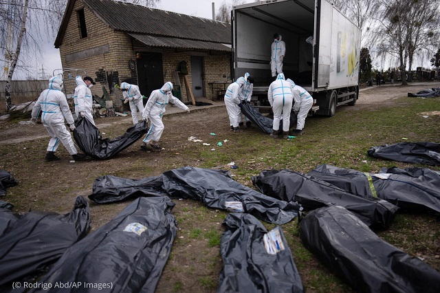 Volunteers load bodies of civilians killed in Bucha onto a truck to be taken to a morgue for investigation near Kyiv, Ukraine, April 12. (© Rodrigo Abd/AP Images)