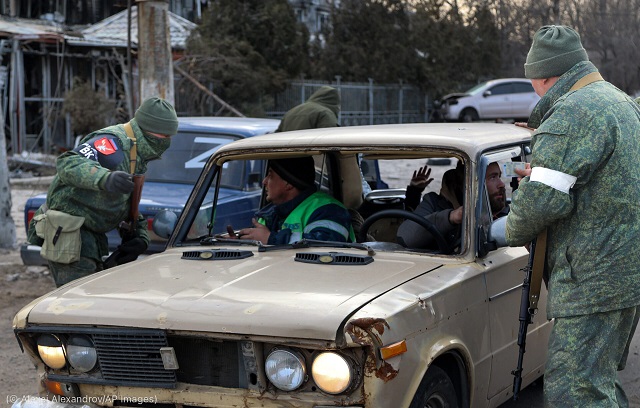 3月27日、ウクライナのマリウポリ郊外の検問所で、車両を調べる武装した「ドネツク人民共和国」の男性 (© Alexei Alexandrov/AP Images)