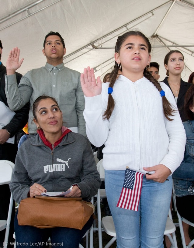 娘のアネリス・ロドリゲスさん（11歳）がアメリカ国籍取得のため宣誓をする様子を見守るリズ・J・クルーズさん（左）。2018年、フロリダ・ビスケーン国立公園にて (© Wilfredo Lee/AP Images)