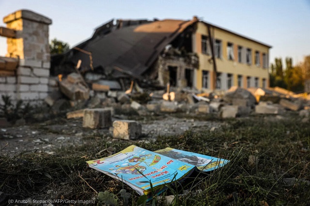 A schoolbook lies near a school destroyed by a missile strike in the Donetsk region August 30. Russia’s invasion displaced 3 million children and caused more than 2 million children to leave Ukraine between February and June, according to UNICEF. (© Anatolii Stepanov/AFP/Getty Images)