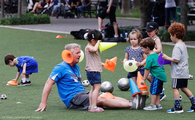 米国の若者の間ではサッカーの人気が高まっている。2017年6月19日、ニューヨークで練習後に子どもたちと片付けをするコーチのマーク・ボーハン (© Mark Lennihan/AP Images)